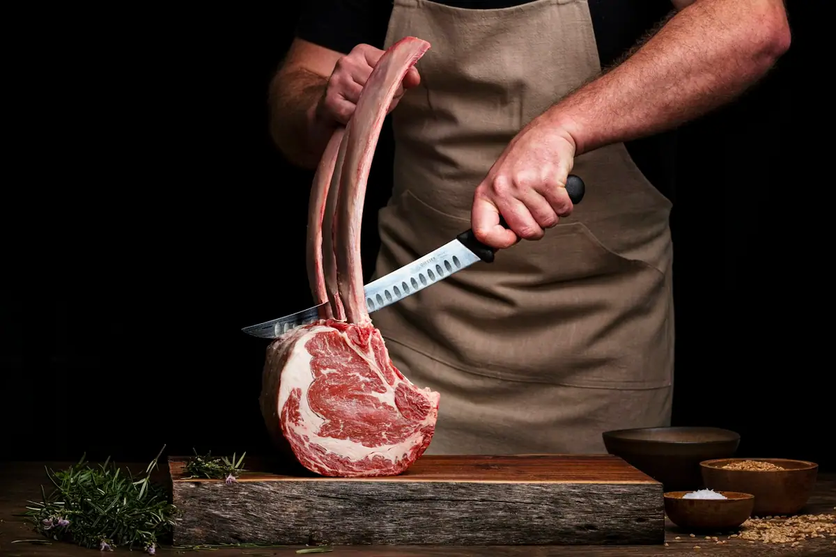 A butcher holding a long-bone tomahawk steak