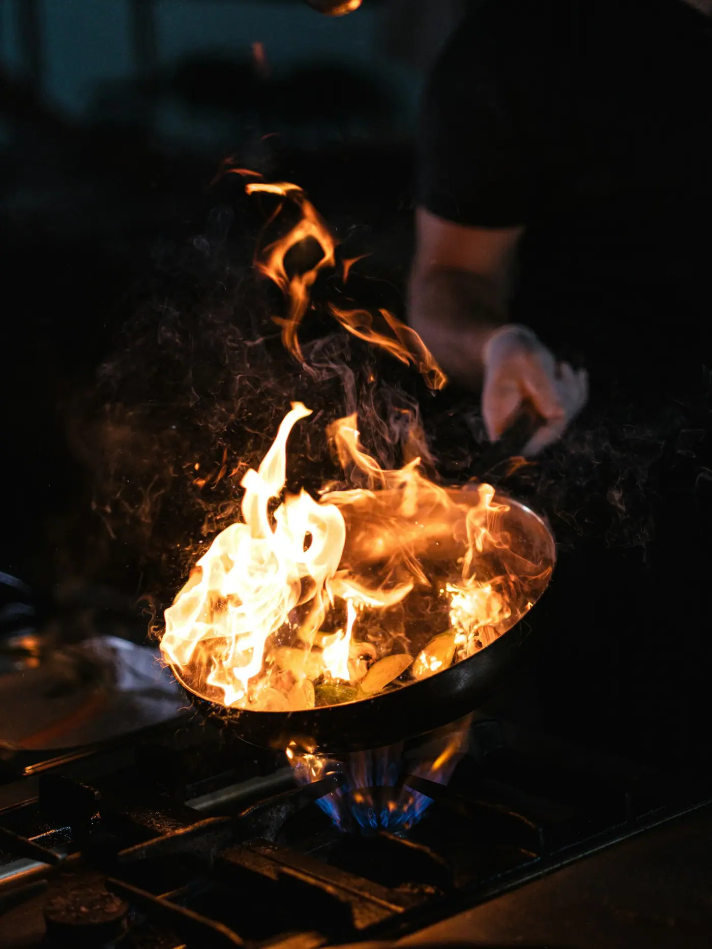 Flames leaping from a pan in a dark kitchen