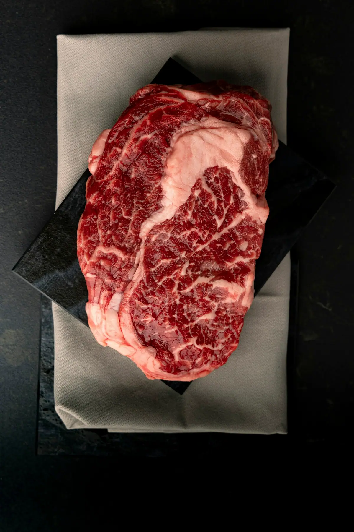 A richly marbled raw beef steak on paper