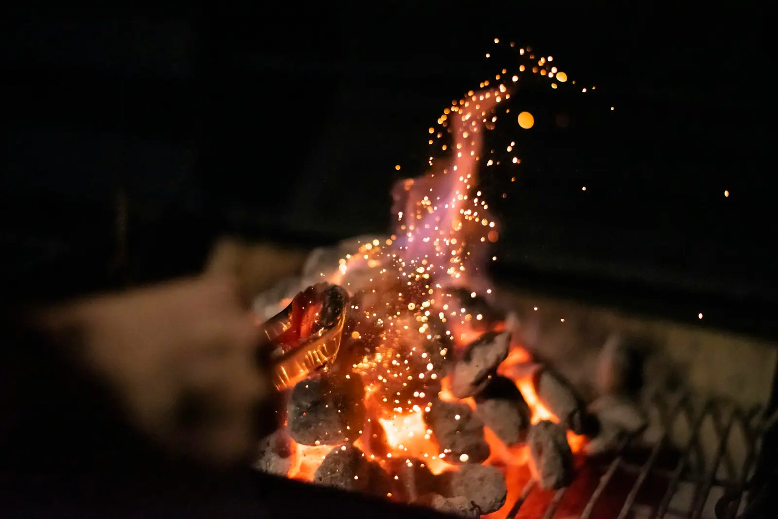 Glowing embers and sparks rising from a fire