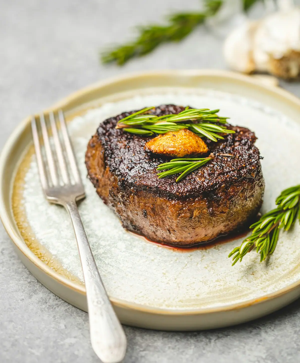 Filet mignon topped with herbs on a white plate