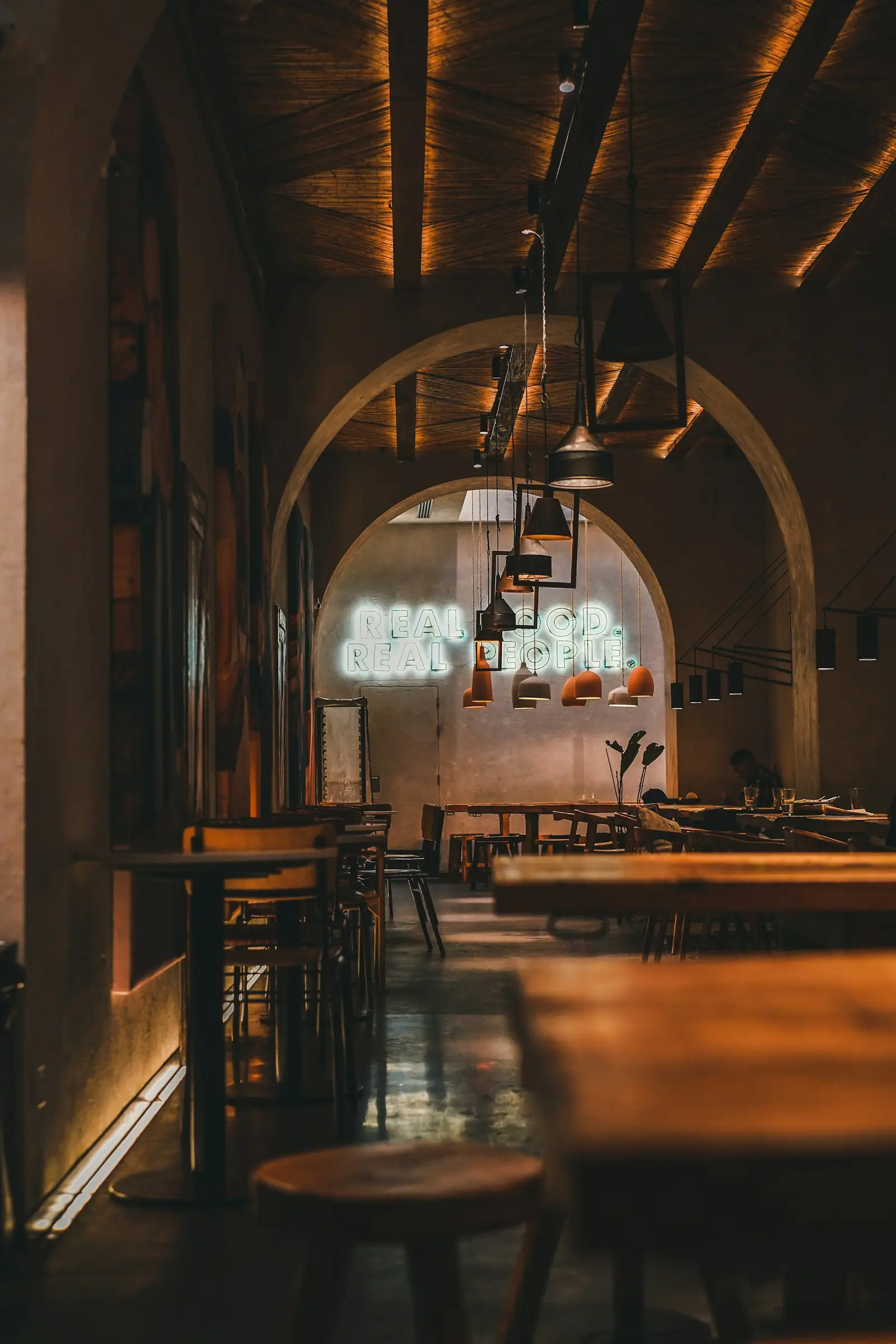A dim, warmly lit dining room with arched walls and set tables
