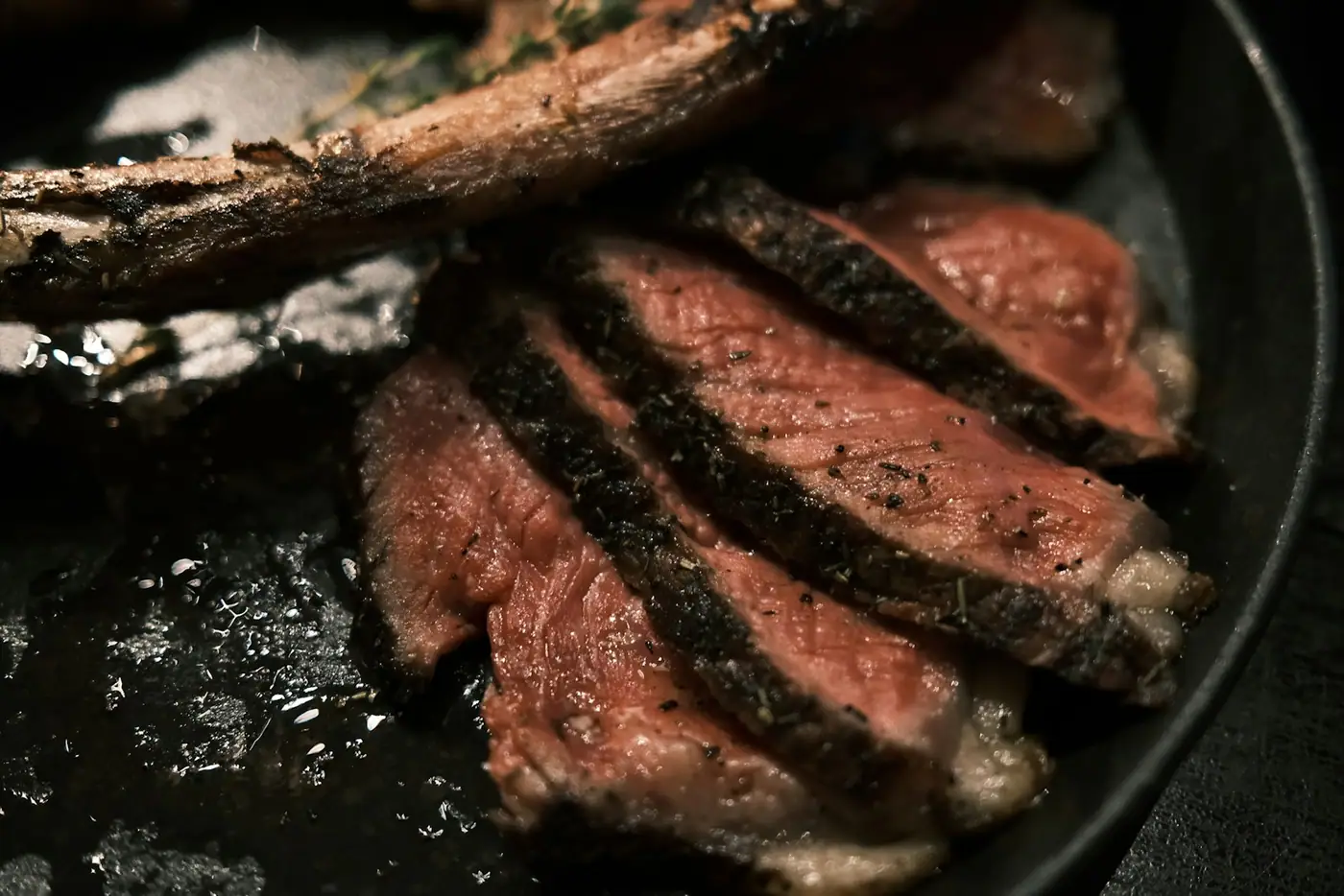 Sliced steak in a cast-iron pan with garlic and herbs
